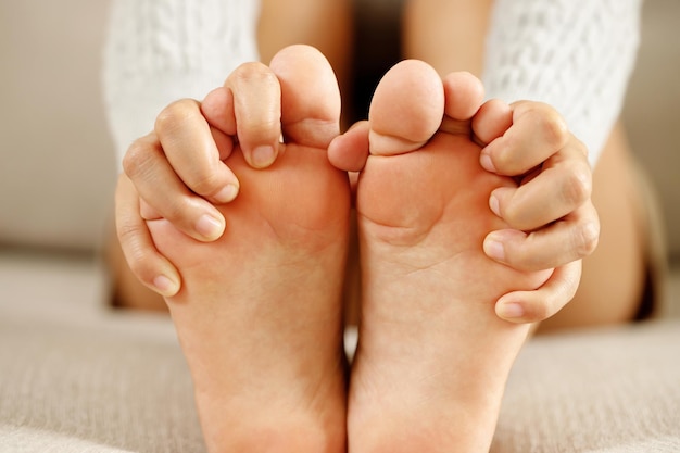 A woman suffering from feeling knee pain sitting sofa at home. hand massaging her painful knee. Health care and medical concept.