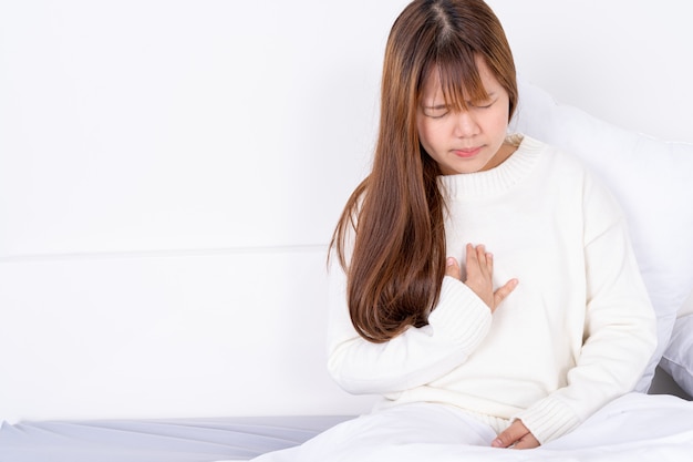 Woman suffering from heart attack or heartburn while sitting