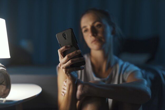 Photo woman suffering from insomnia and checking her phone