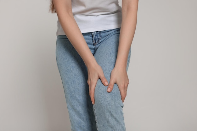 woman suffering from pain in her knee on light grey background closeup arthritis symptoms