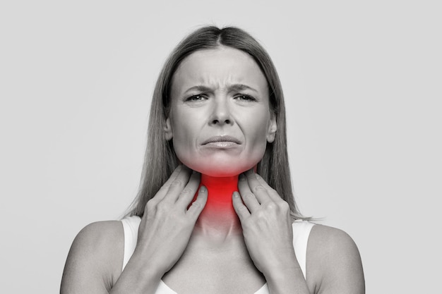 Woman suffering from sore throat touching her neck
