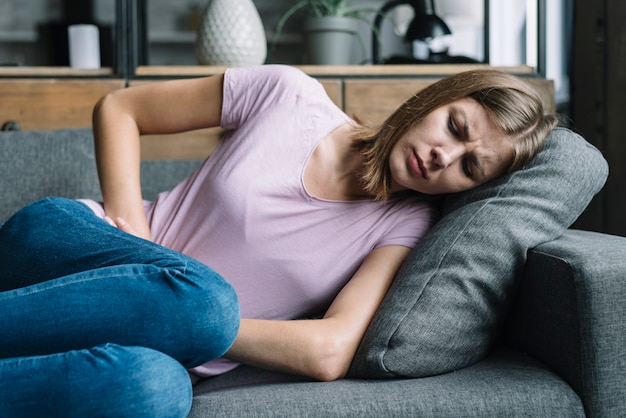 Foto donna che soffre di mal di stomaco sdraiato sul divano