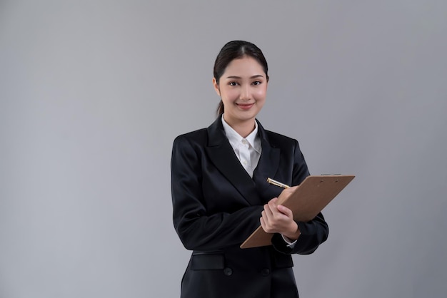 A woman in a suit is holding a clipboard and smiling.