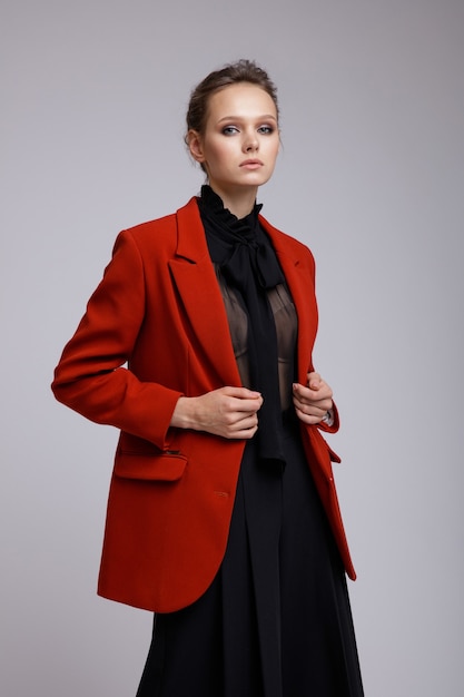Woman in suit red jacket black transparent blouse short pants on white soft gray background