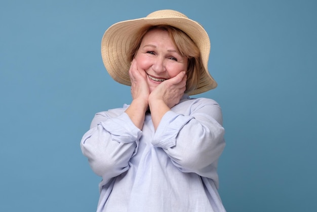 Woman in summer hat looking with smile pleased to hear a compliment to flowers