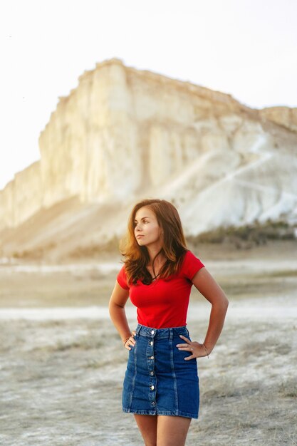 Woman in the sunset on the background of a white rock