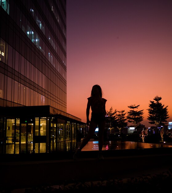 建物の近くの日没の女性