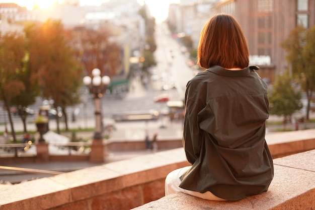 素晴らしい街の景色、暖かい日、自由、ポジティブな雰囲気を楽しんでいる日没の女性