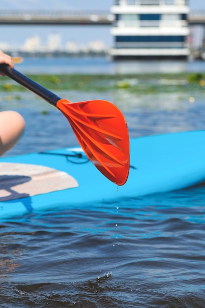 Foto donna su una tavola di sup sul fiume che rema sull'acqua