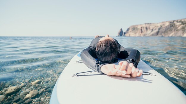 Woman sup yoga happy sporty woman practising yoga pilates on paddle sup surfboard female stretching