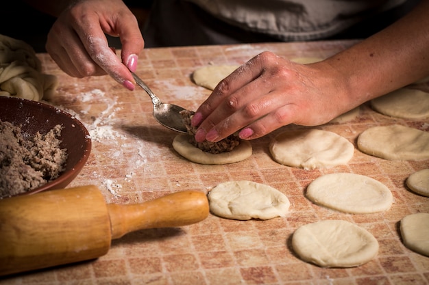 Женщина накладывает мясную начинку