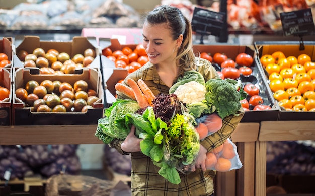 Woman in the supermarket. Beautiful young woman shopping in a supermarket and buying fresh organic vegetables