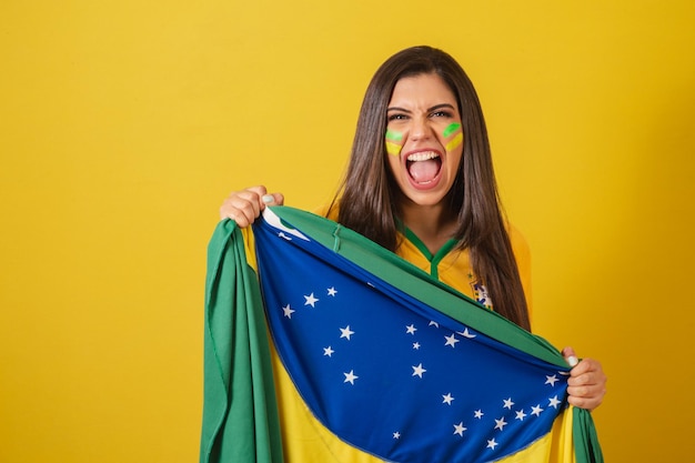 Woman supporter of brazil world cup 2022 football championship\
holding flag screaming goal and cheering partying celebrating