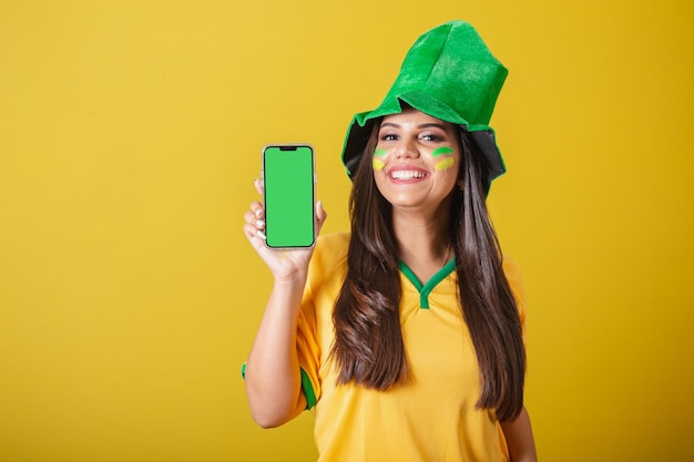 Woman supporter of Brazil world cup 2022 holding cellphone showing screen for app and technology ads promotions