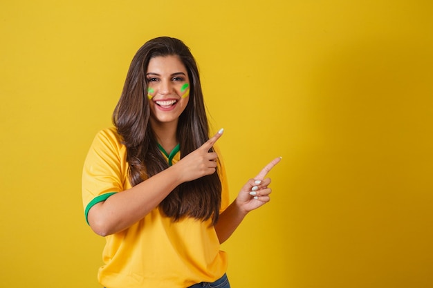Woman supporter of Brazil world cup 2022 soccer championship presenting product with fingers to the right