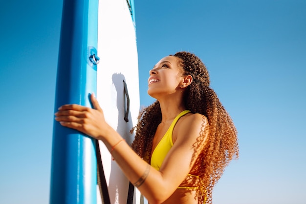 Woman surfer walks with a board on the sandy beach Extreme sport Travel weekend lifestyle