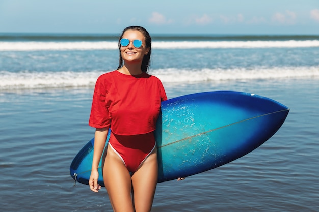 Surfista donna con shortboard sulla spiaggia