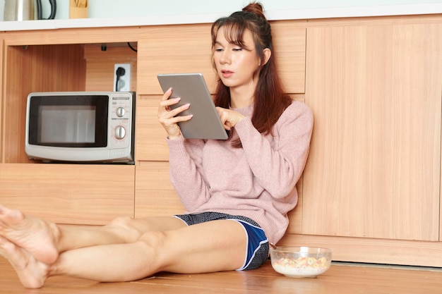 朝食時にネットサーフィンをする女性