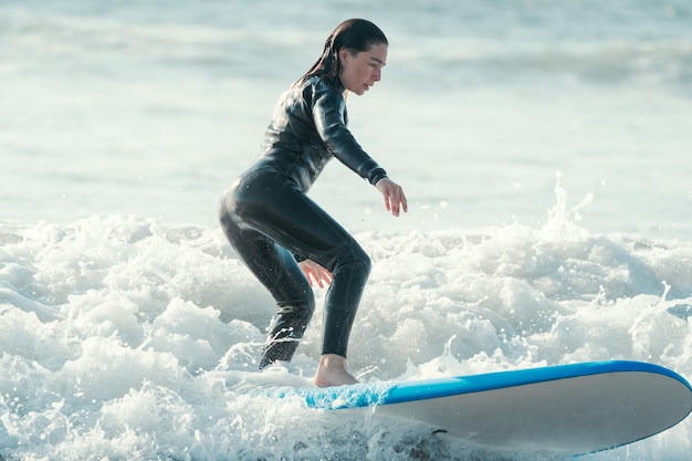 Donna che pratica il surfing sul ritratto dell'onda