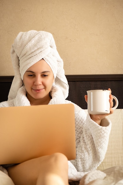 Woman surfing the web after showering with a cup of coffee in the morning