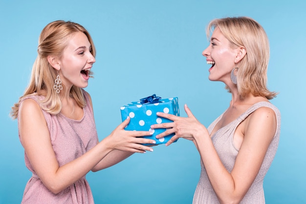 Photo woman surprising friend with gift