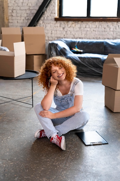 Photo woman surrounded by cardboard boxes after moving in to her new home