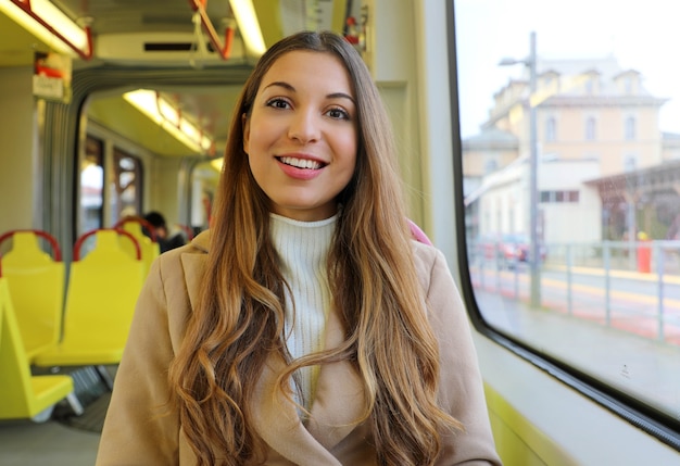 Woman in sweater and coat sitting in the tram smiling at camera