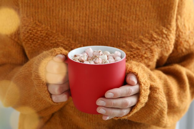 Woman in sweater hold cup of cocoa