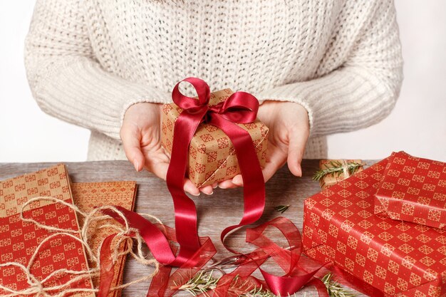 Woman in sweater holding wrapped Gifts in hands