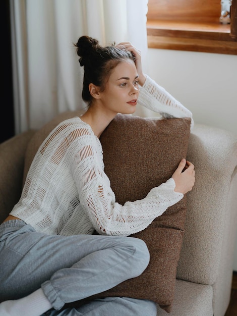 Woman in sweater and home pants relaxing lying on the couch at home cozy day off in comfort real lifestyle with a smile