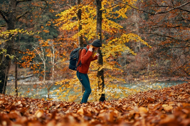 Woman in a sweater jeans and with a hat on her head landscape fallen leaves model