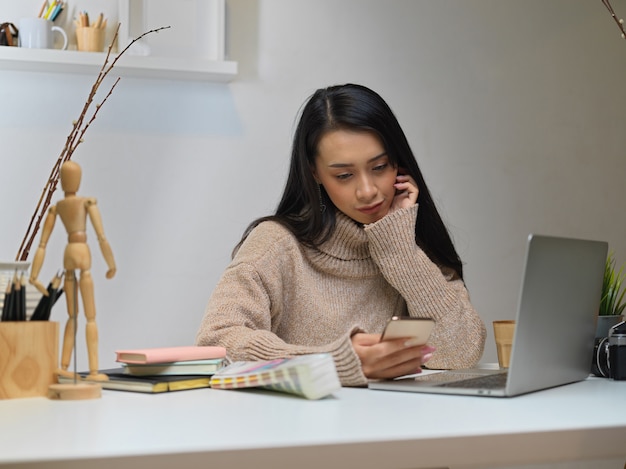 スマートフォンを使用してセーターの女性