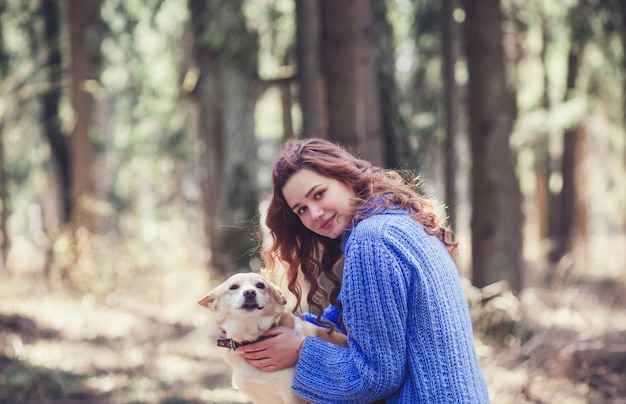 Woman in sweater with dog in forest