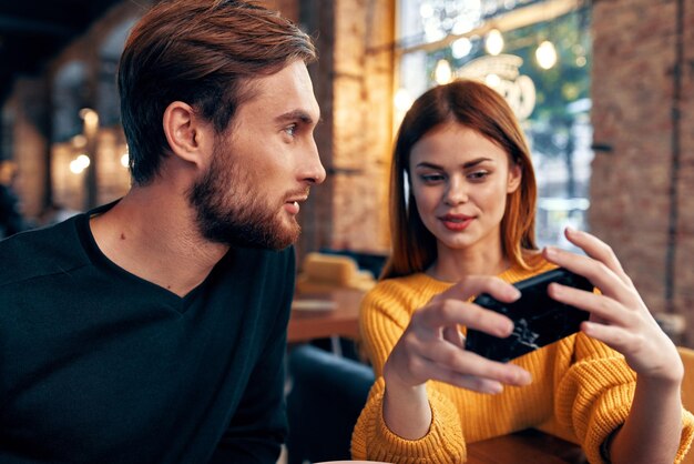 照片的女人一件毛衣一部手机和一个男人有胡须的坐在一家餐馆