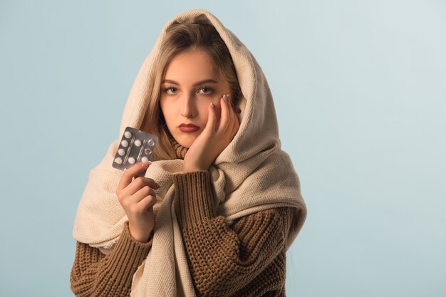 woman in a sweater with pills in hands