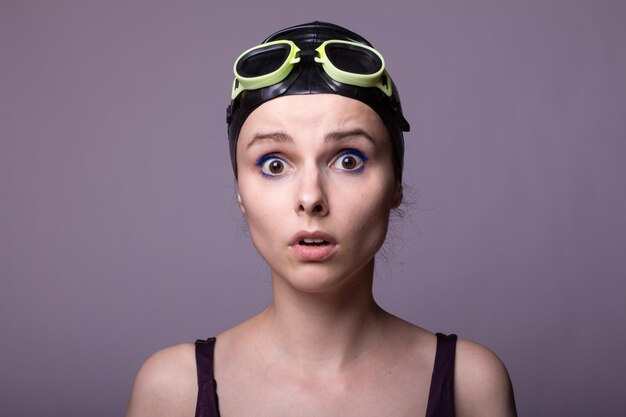 woman swimmer in a swimming cap glasses and a swimsuit gray background