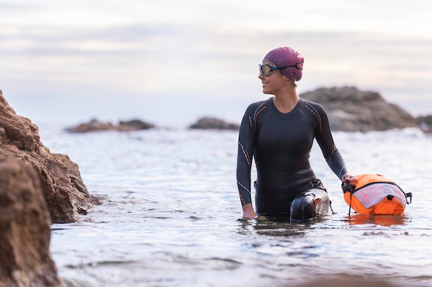 ウェットスーツとブイを使ってオープンウォーターで泳ぐ女性