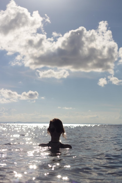 空に逆らって海で泳ぐ女性