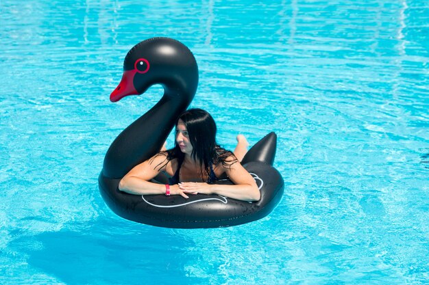 A woman swims on a lifebuoy in the pool. Summer heat blue water