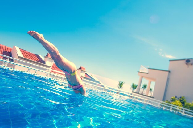 Woman in a swimsuit dives into pool in the sunlight Toned