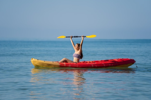 Woman in swimsuit paddling a kayak boat in the sea