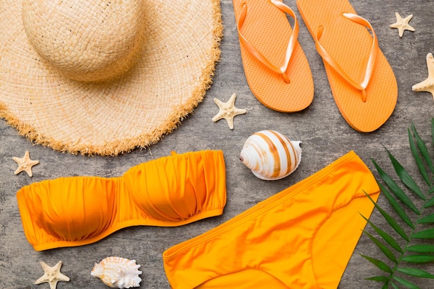 Photo woman swimwear and beach accessories flat lay top view on colored background summer travel concept bikini swimsuit straw hat and seasheels copy space top view