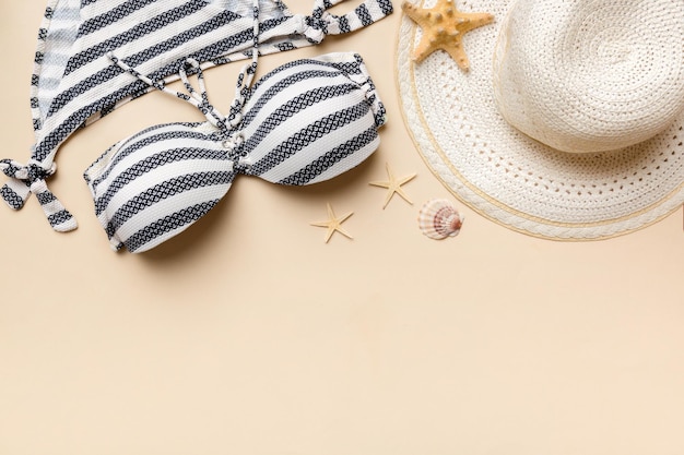 Photo woman swimwear and beach accessories flat lay top view on colored background summer travel concept bikini swimsuit straw hat and seasheels copy space top view