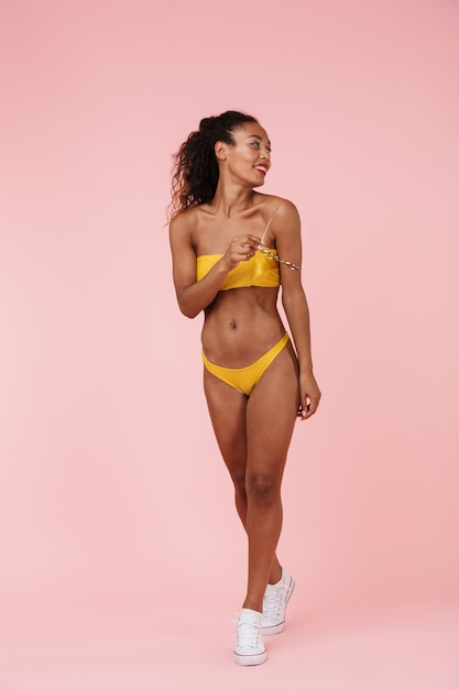 Woman in swimwear posing isolated over pink wall