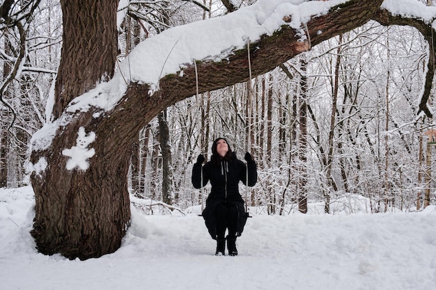 Foto una donna su un'altalena in una foresta innevata