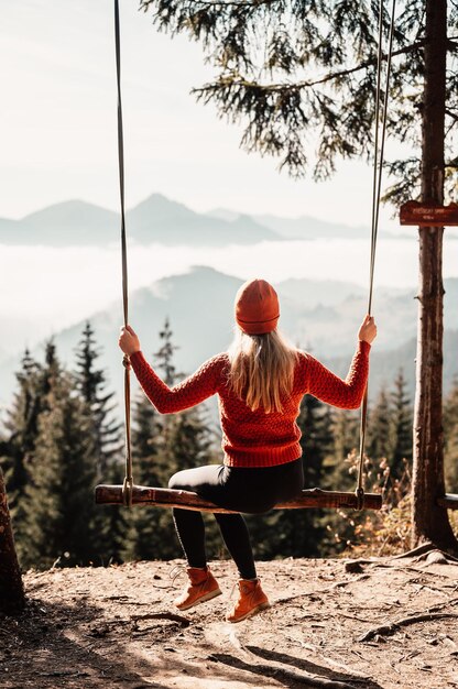 Woman swinging on swing in sunny winter dayin the ferest Wooden swing with swinging free happy woman outdoors Healthy lifestyle vacation Zazriva slovakia