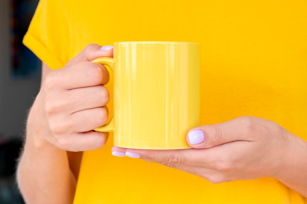 Photo woman in t-shirt holding a warm cup of coffee