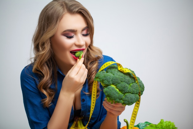 Photo woman at table holding a broccoli on of fruit and vegetables