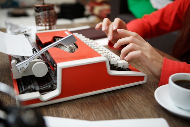 Woman at table typing on typewriter