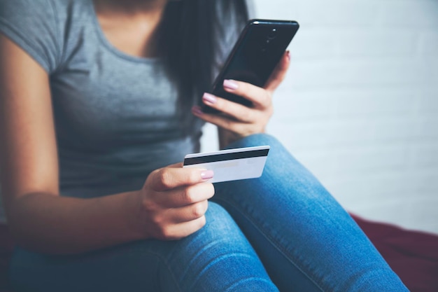 Woman take credit card and look phone on the bed